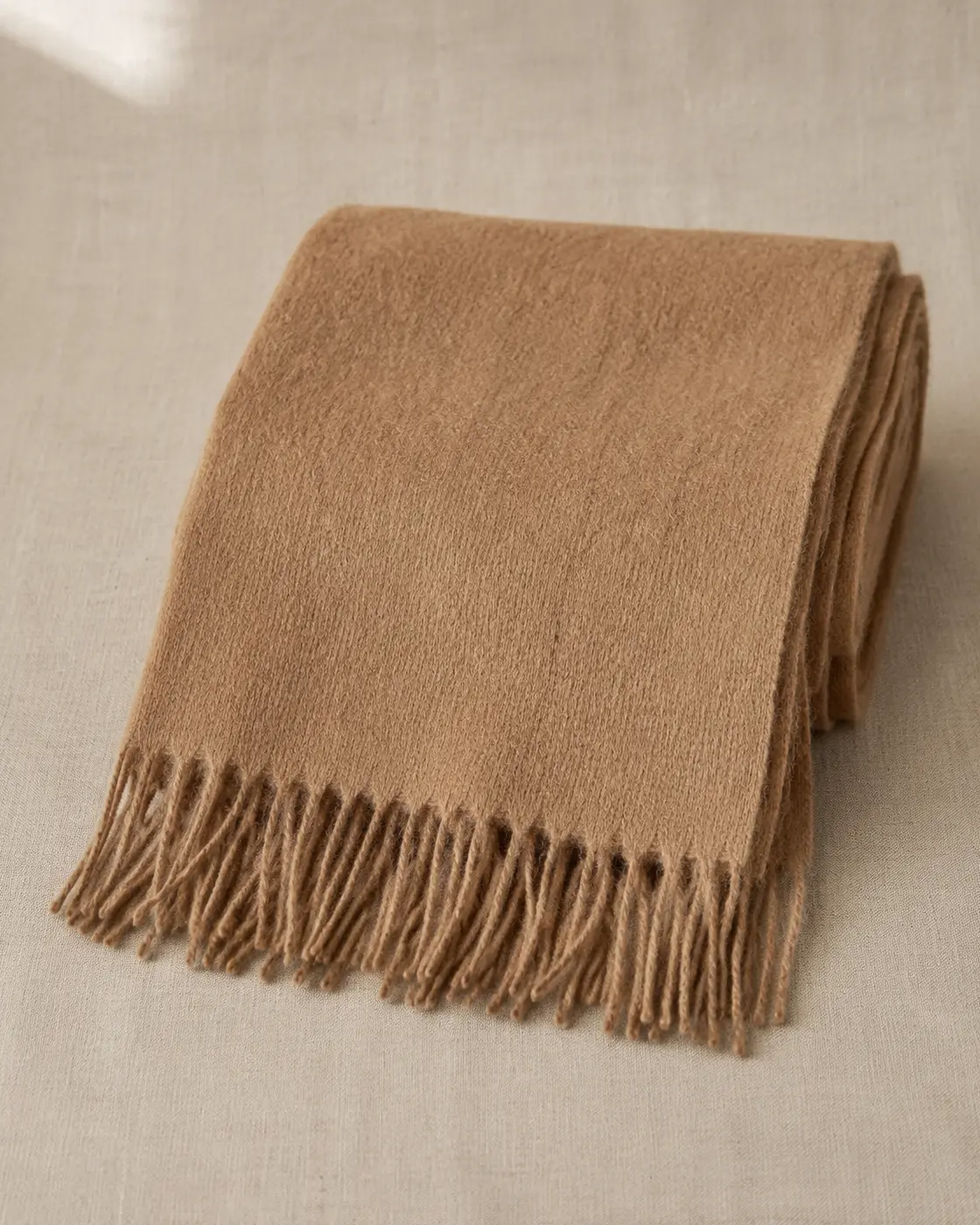 Detalle de bufanda camel sobre lino crudo